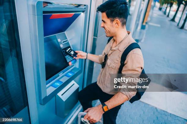 tourist at the atm withdrawing money with a smartphone - contactless payment stock pictures, royalty-free photos & images