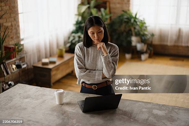 focused woman contemplating in a stylish home office environment - warm light stock pictures, royalty-free photos & images
