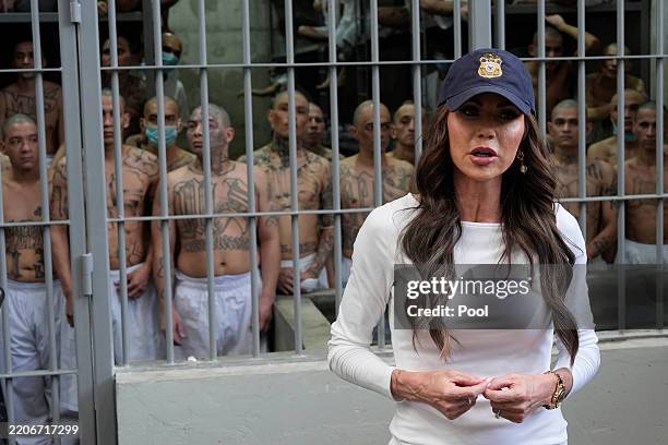 As prisoners stand looking out from a cell, Department of Homeland Security Secretary Kristi Noem speaks during a tour of the Terrorist Confinement...