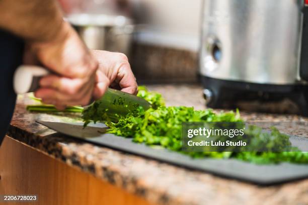 chef cutting fresh parsley on kitchen countertop - chopped herbs stock pictures, royalty-free photos & images