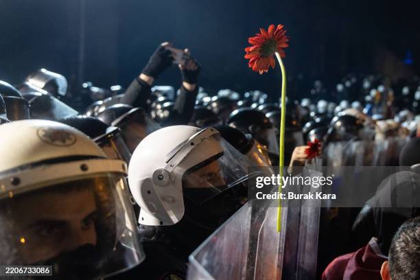 Demonstrator attaches a flower to the shield of the police during the protests in front of Istanbul's famous Aquaduct on March 24, 2025 in Istanbul,...