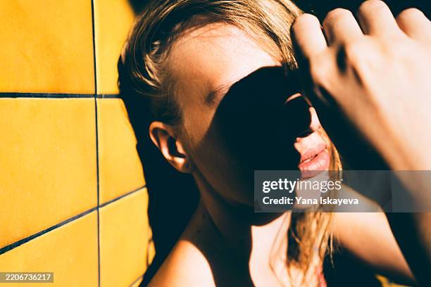 sunlit portrait with dramatic shadows on a yellow tiled background - schoonheidsspecialist natuur stockfoto's en -beelden