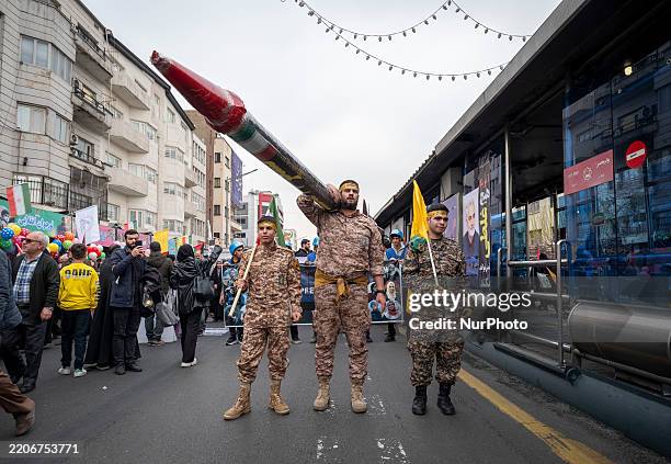Islamic Revolutionary Guard Corps military personnel stand together as one of them holds a scale model missile during a rally commemorating...