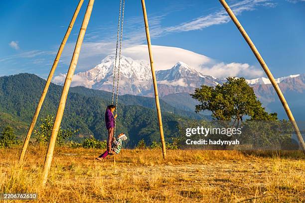 children swinging in village near pokhara, himalayas on background, nepal - nepal family stock pictures, royalty-free photos & images