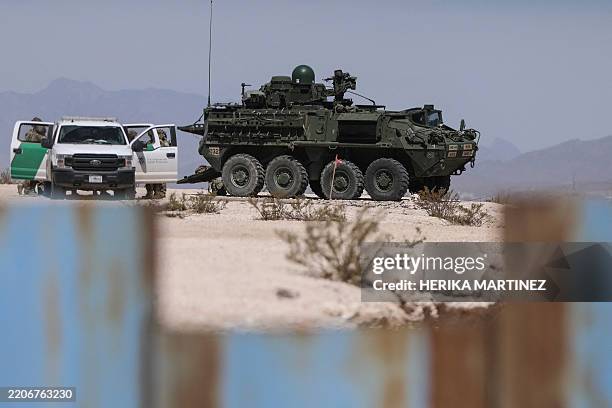 Border Patrol agents and an eight-wheeled Stryker armored vehicle patrolling the border area in Sunland Park, New Mexico state, U.S., are seen from...