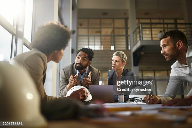 diverse project managers talking while working on plans at construction site. - structural engineer stock pictures, royalty-free photos & images