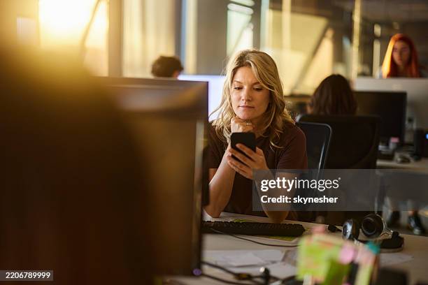 female programmer using smart phone in the office. - plataforma de mensagens online com marca registrada imagens e fotografias de stock
