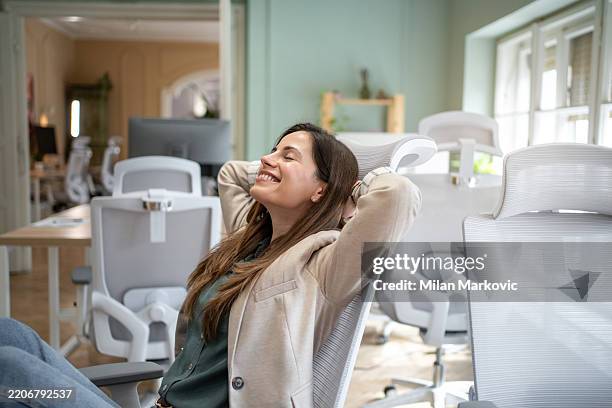 businesswoman relaxing on ergonomic office chair: feeling comfortable and stress-free - ergonomie stockfoto's en -beelden
