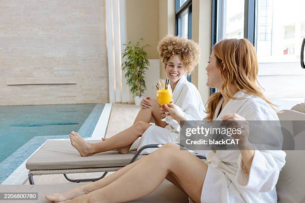 donne che si godono bevande rinfrescanti in una spa che si rilassano su sedie a sdraio - bordo piscina foto e immagini stock