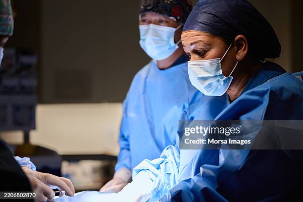 female surgeon leading a critical procedure - surgical cap stock pictures, royalty-free photos & images