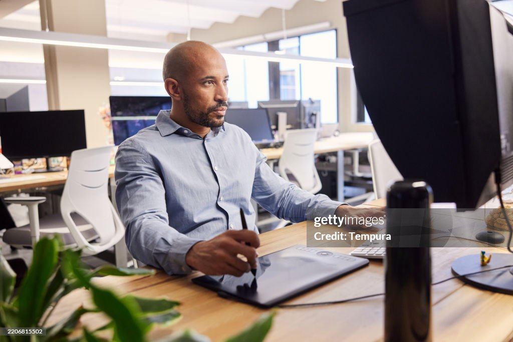 A man working on a desktop computer using a digital pen.