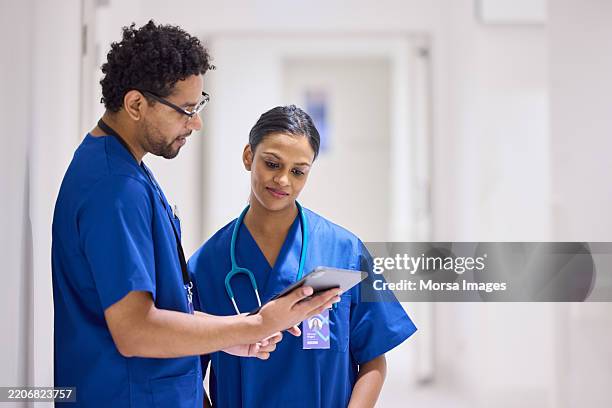 male nurse discussing with colleague through tablet pc - female nurse stock pictures, royalty-free photos & images