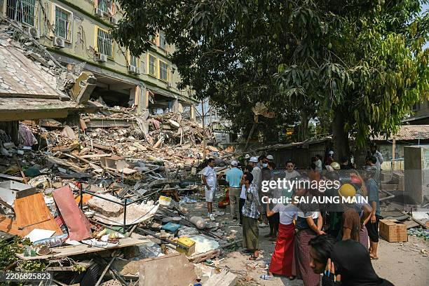 People look on as teams of rescue workers attempt to free residents trapped under the rubble of the destroyed Sky Villa Condominium development in...