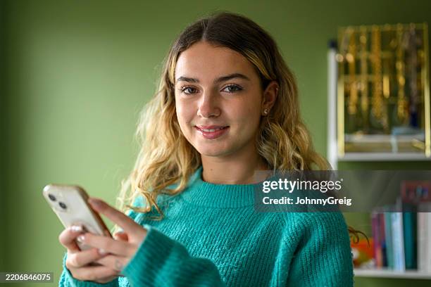 mujer haciendo una pausa de los mensajes de texto para sonreír a la cámara - sólo una adolescente fotografías e imágenes de stock