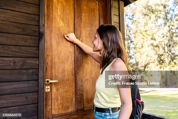 giovane donna che bussa alla porta della casa - bussare foto e immagini stock