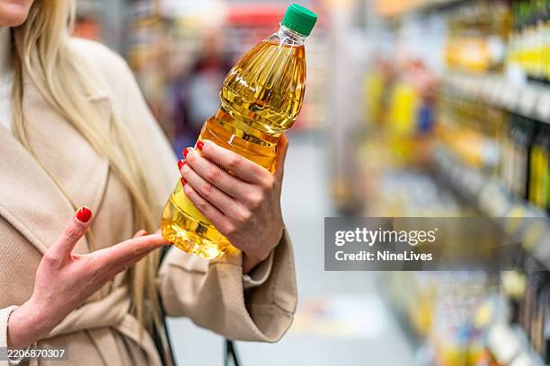 femme choisissant l’huile de tournesol au supermarché - huile de table photos et images de collection