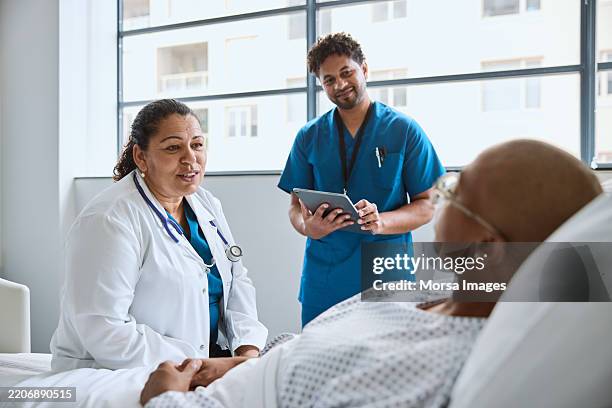 femme médecin souriante assise à côté de la femme dans la clinique - cellule cancéreuse photos et images de collection