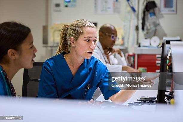 nurses using computer at desk in hospital - nurse stockfoto's en -beelden