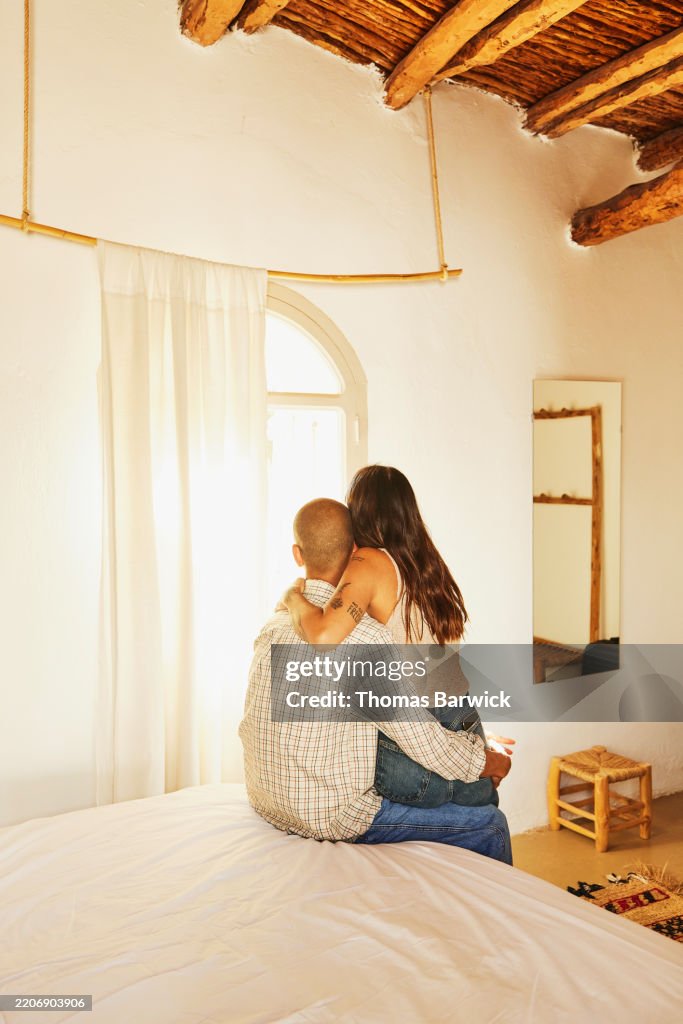 Wide shot woman sitting on lap of boyfriend while relaxing in bedroom