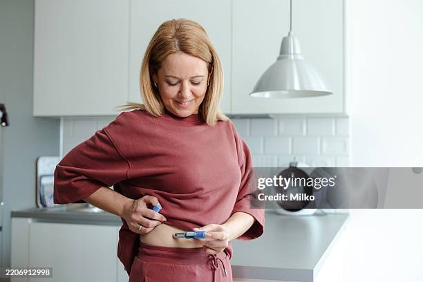 woman administering a medical injection in a bright home kitchen setting - fazer dieta imagens e fotografias de stock