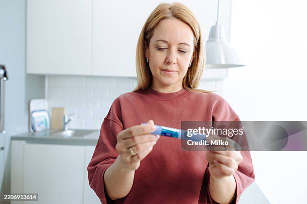 woman holding an insulin pen and preparing for diabetes care management at home - injection pen stock pictures, royalty-free photos & images