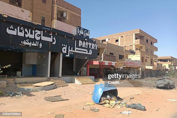 Picture shows a destroyed car next to damaged shops in a southern neighbourhood of Khartoum on March 29 after the military recaptured the capital....