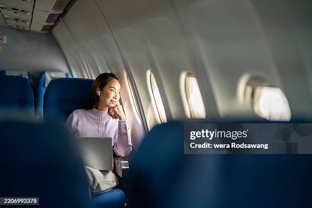 a business woman admires the scenic views from her airplane window - business class imagens e fotografias de stock