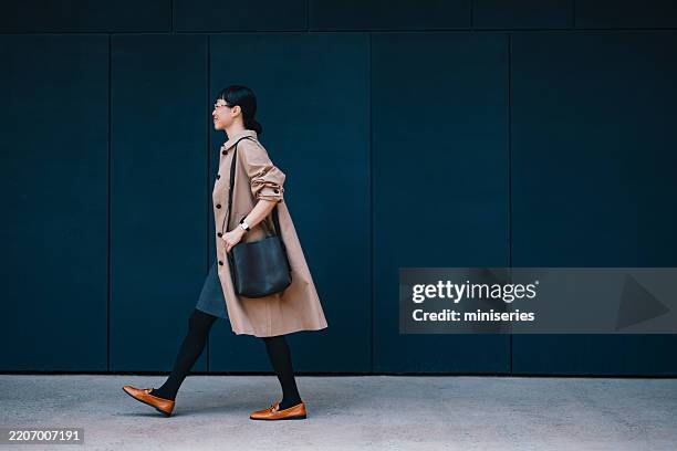 confident businesswoman walking alongside urban building in modern city - blue shoe stock pictures, royalty-free photos & images