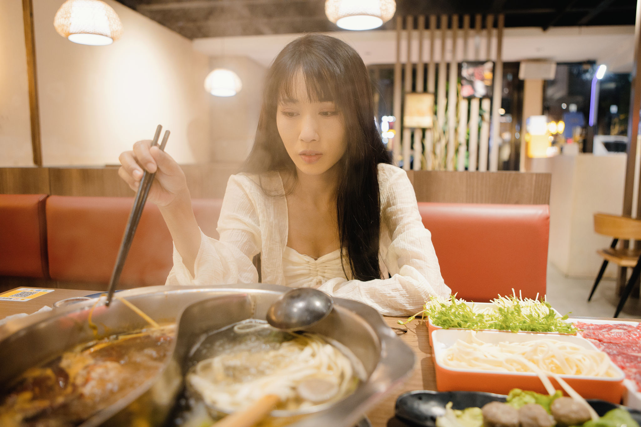 An Asian woman is eating beef hotpot, Chinese cuisine, and nightlife at a restaurant An Asian woman is eating beef hotpot, Chinese cuisine, and nightlife at a restaurant