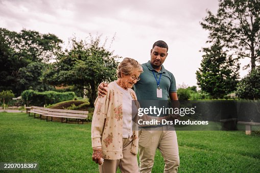 Voluntario caminando en el jardín con una anciana en un hogar de ancianos Voluntario caminando en el jardín con una anciana en un hogar de ancianos