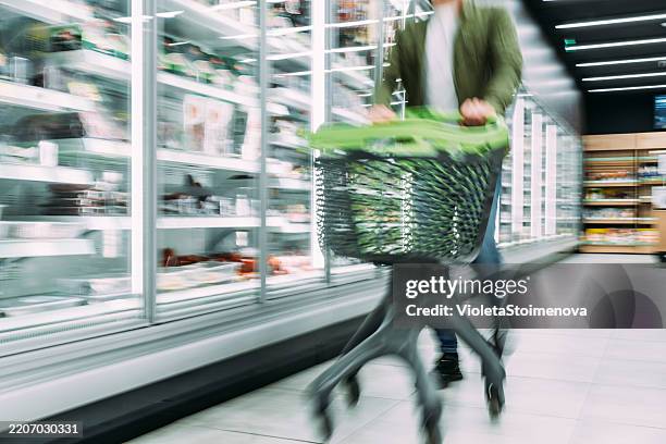 busy customer pushing shopping cart at the supermarket. - overloaded shopping cart stock pictures, royalty-free photos & images