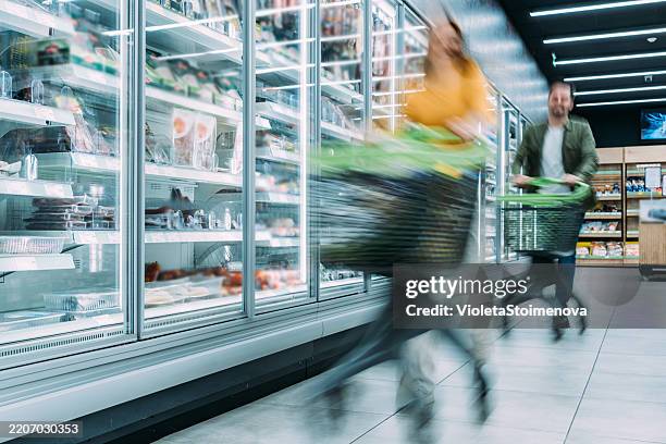busy customers pushing shopping carts at the supermarket. - overloaded shopping cart stock pictures, royalty-free photos & images