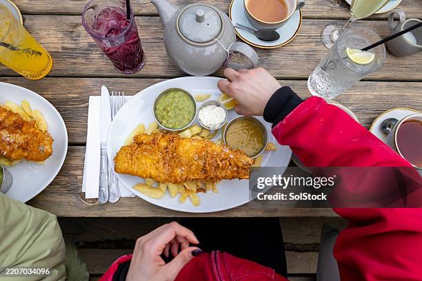 a perfect meal of fish and chips outdoors with friends - fish and chips stock pictures, royalty-free photos & images