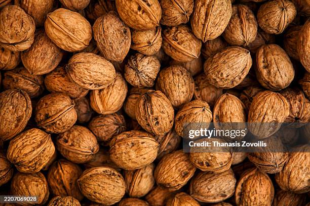 walnuts in their shells arranged on a wooden surface - nozes imagens e fotografias de stock
