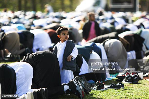 Young boy looks up as he joins Muslim worshippers taking part in the Eid al-Fitr morning prayer to mark the end of the Holy month of Ramadan in...