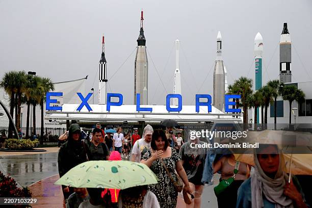 Visitors with umbrellas leave the Kennedy Space Center Visitor Complex on a rainy day on August 17, 2023 in Merritt Island, Florida.