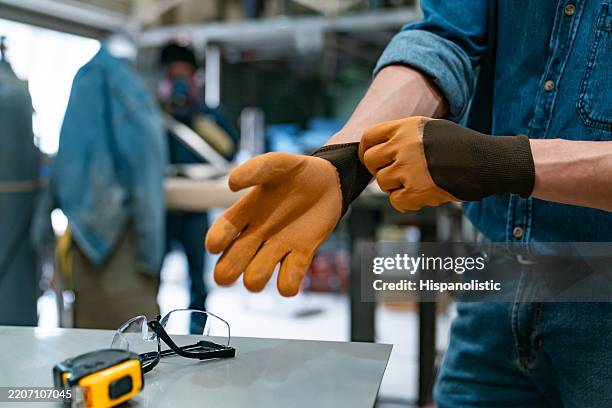 trabajador de fabricación colocando sus guantes de trabajo en la fábrica - guantes-de-trabajo fotografías e imágenes de stock