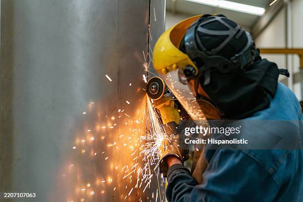 métallurgiste à l’aide d’une meuleuse pour couper une tôle d’acier inoxydable - tôle photos et images de collection