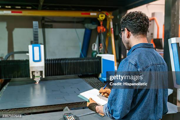 technician supervising the operation of a laser cutting machine at a metal factory - laser engraving stock pictures, royalty-free photos & images