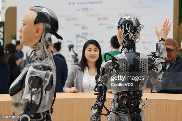 Journalist interacts with humanoid robots at an information desk at Zhongguancun International Innovation Center, venue for the 2025 Zhongguancun...