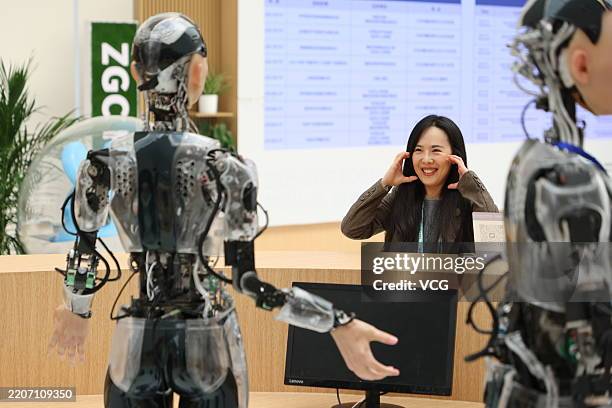 Journalist interacts with humanoid robots at an information desk at Zhongguancun International Innovation Center, venue for the 2025 Zhongguancun...