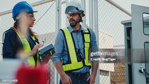 engineers connect electrical system outdoors. two electricians in protective uniform checking voltage on the solar power plant. - emergency plan stock pictures, royalty-free photos & images