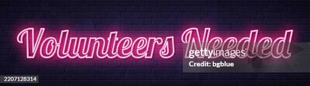 volunteers needed - glowing neon text on brick wall background - need help stock illustrations