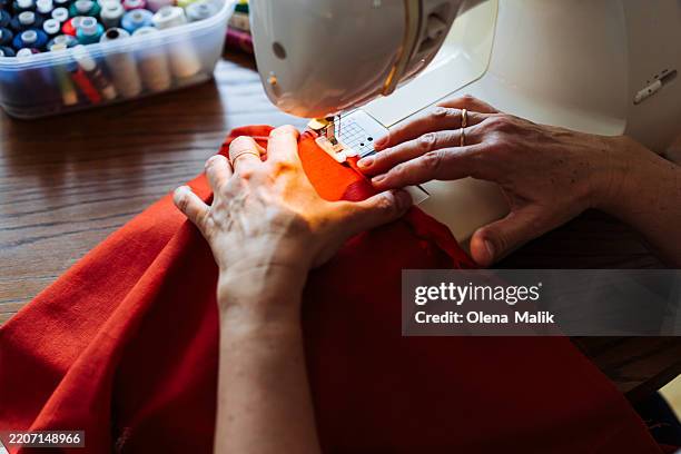 woman sewing fabric using a machine in a cozy indoor setting - patchwork stock pictures, royalty-free photos & images