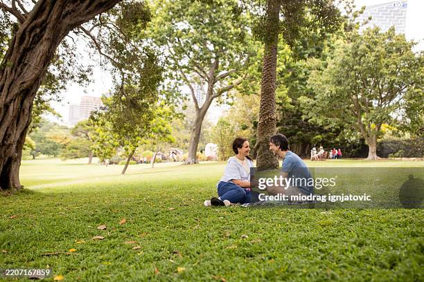happy couple enjoying picnic on meadow in the park - picnic park stock pictures, royalty-free photos & images