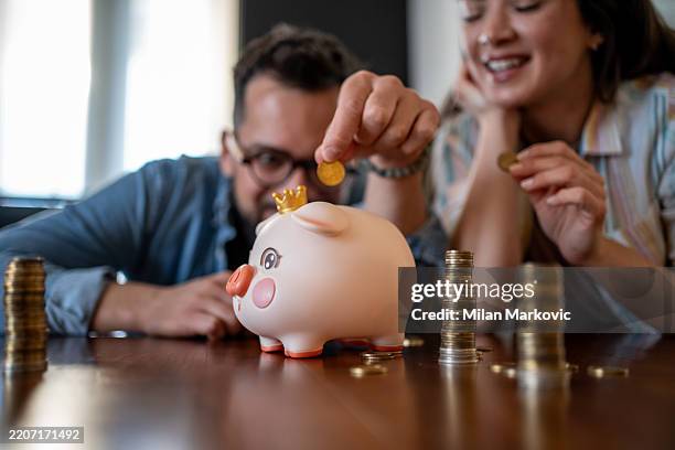young couple saving money together with piggy bank - interest rate stock pictures, royalty-free photos & images