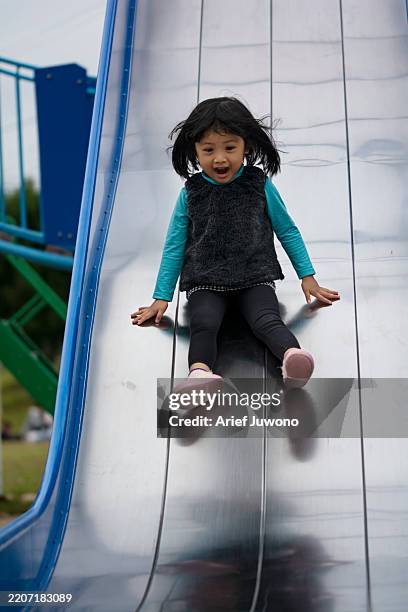 happy girl playing on a slide in the park - kid sliding stock pictures, royalty-free photos & images