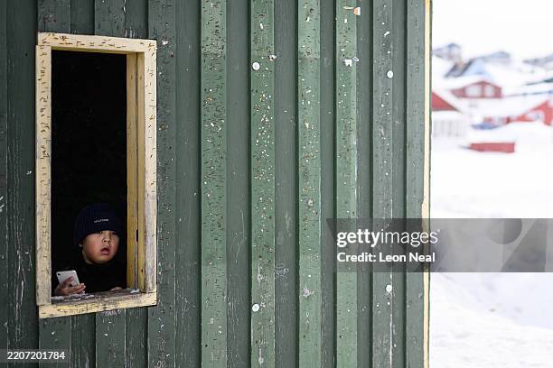 Young boy looks from the window of a bus shelter on March 27, 2025 in Nuuk, Greenland. A visit this week to Greenland by a US delegation - including...