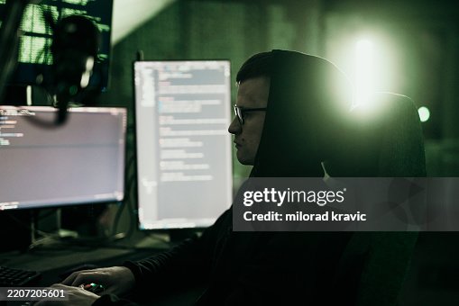 Hacker working on multiple computer screens with green light Hacker working on multiple computer screens with green light
