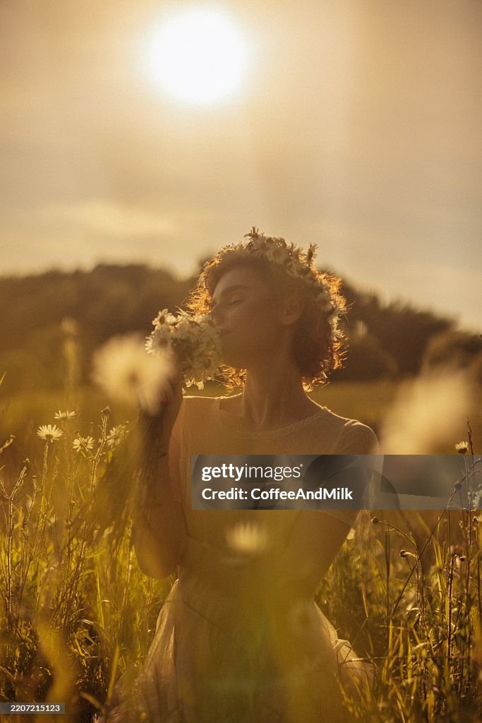 Beautiful girl in a field with a bouquet of flowers and a wreath